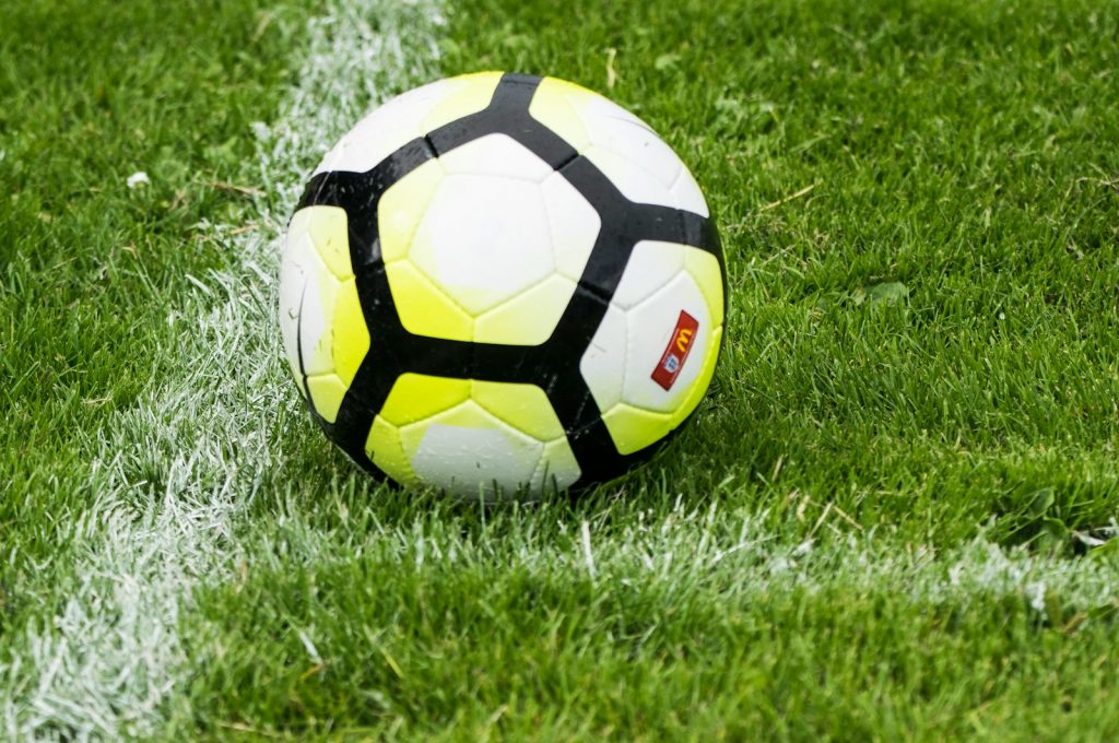 white and green soccer ball on grass
